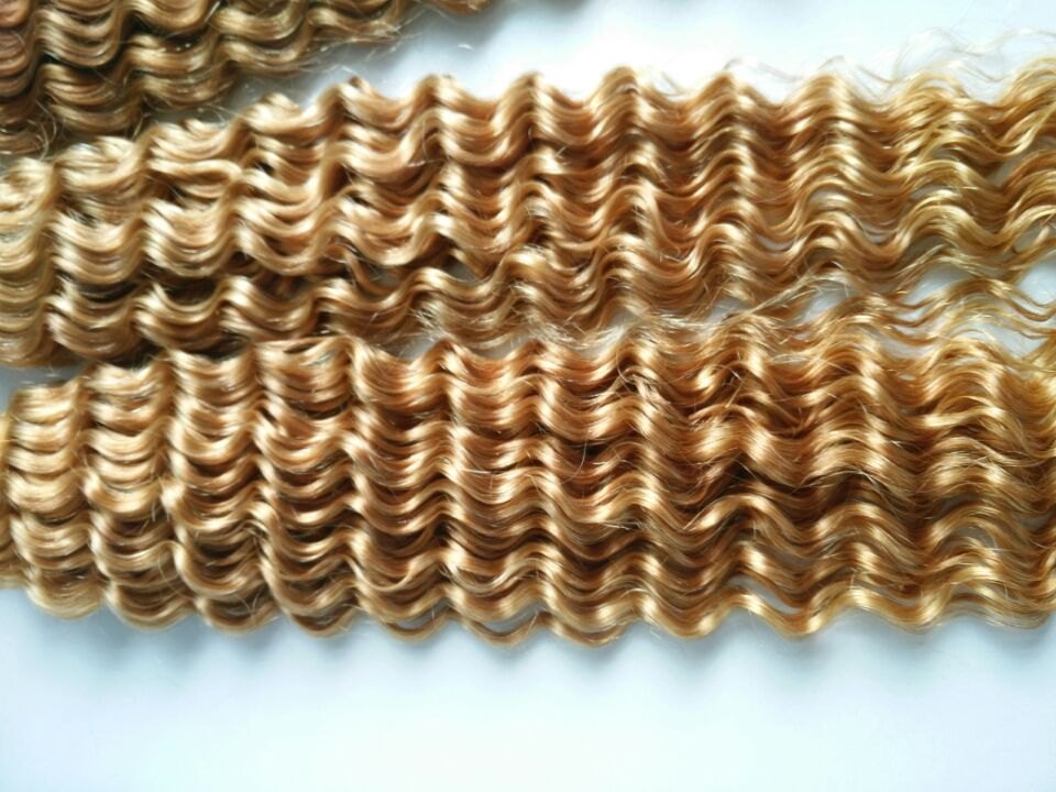 Close-up van lichtgekleurde extensions met een regelmatig patroon van kleine diepe golven.