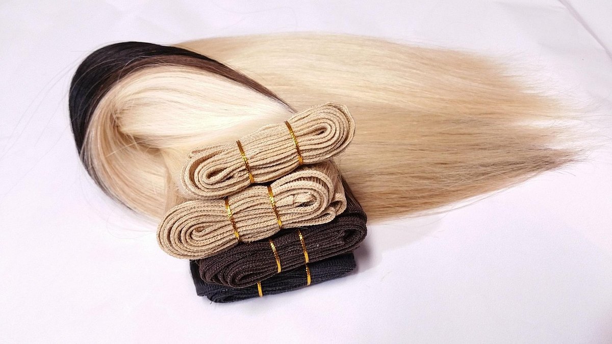 Opgevouwen donkere en blonde haarbanen met de gestikte bovenranden duidelijk zichtbaar.