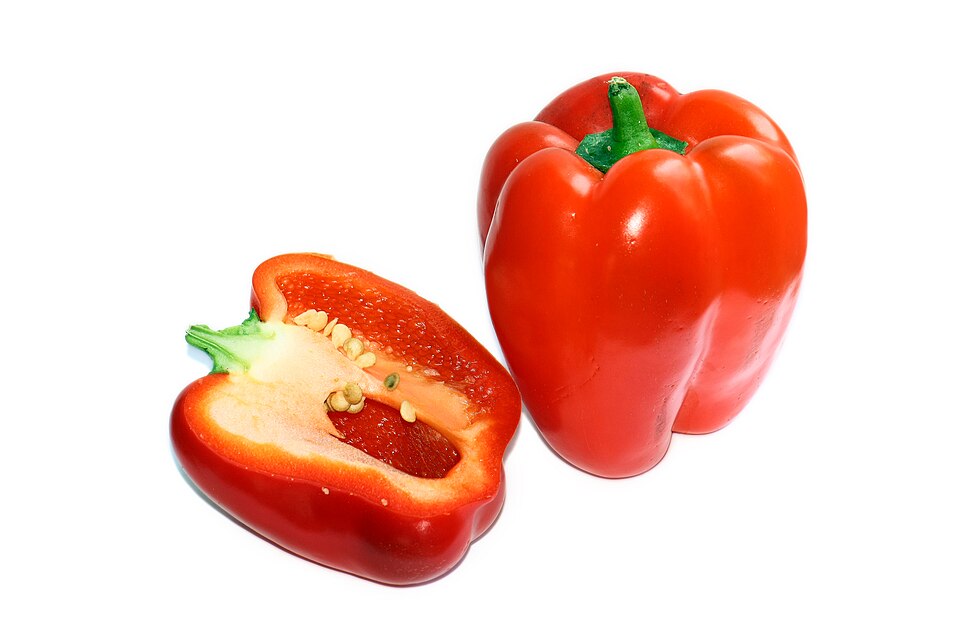 Een hele en een doorgesneden rode paprika